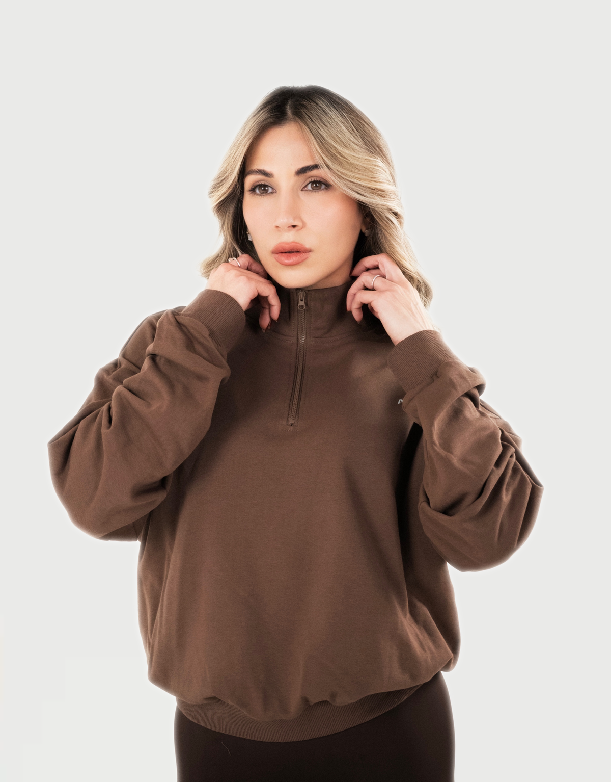 Zip Pullover AVA en color marrón, detalle frontal del cuello alto y cierre.