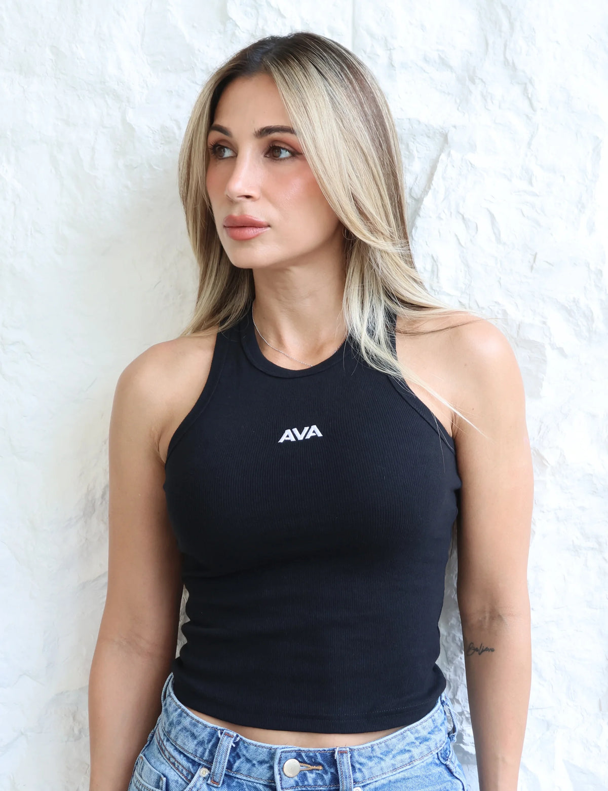 Tank Top AVA en color negro, detalle frontal del cuello y el logo AVA.